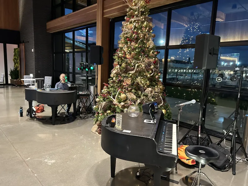 Two grand pianos set up in a hotel lobby with a Christmas tree between them