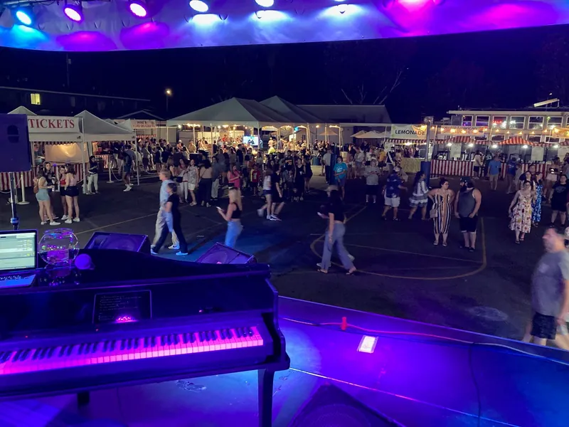 Piano setup with purple lights overlooking a packed outdoor dance floor