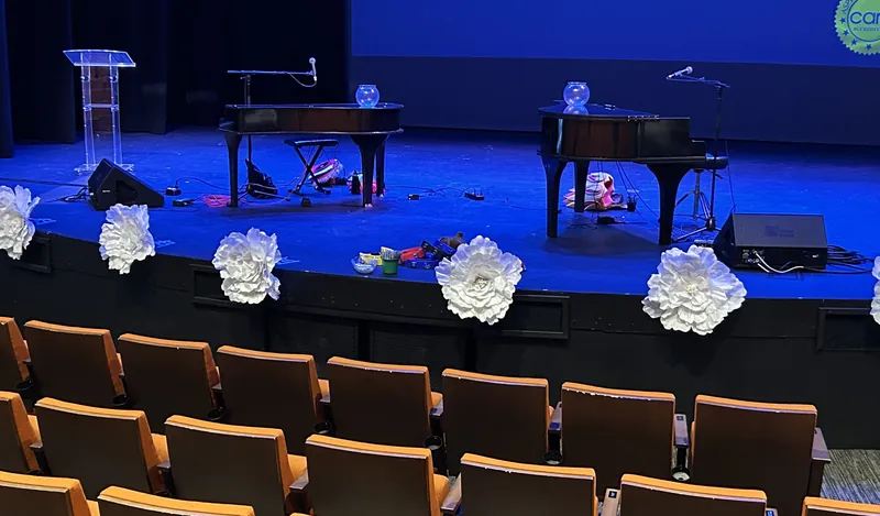 Two grand pianos on a theater stage lit in blue for a nonprofit event