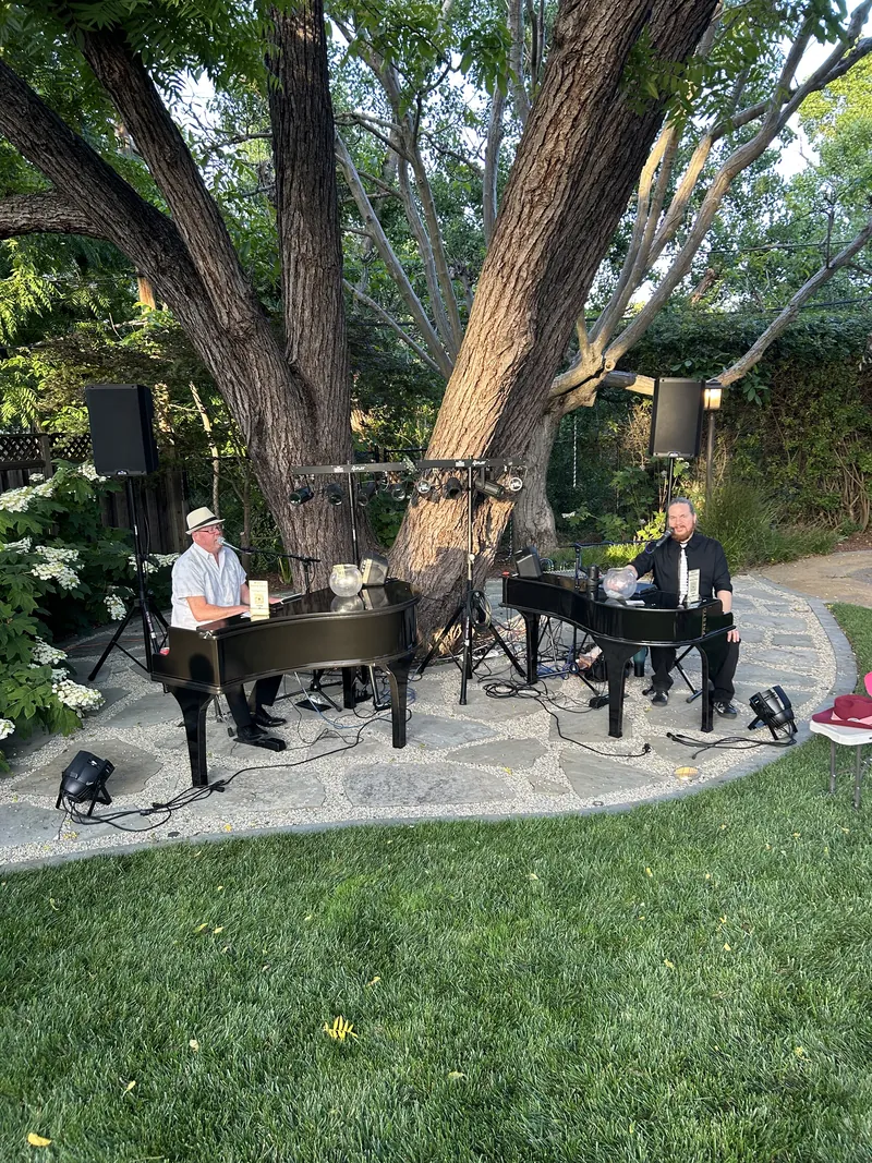 Two piano shells under a large oak tree on a garden patio