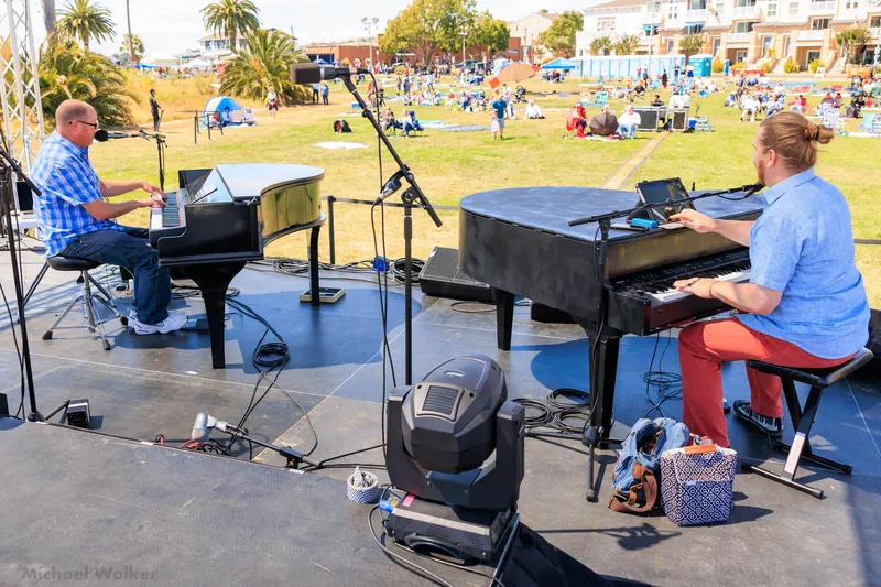 Two pianos on an outdoor lawn stage with stage lights
