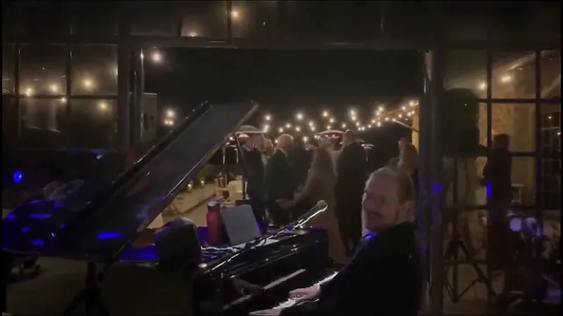 Wedding reception at night: guests dancing under string lights beside the piano